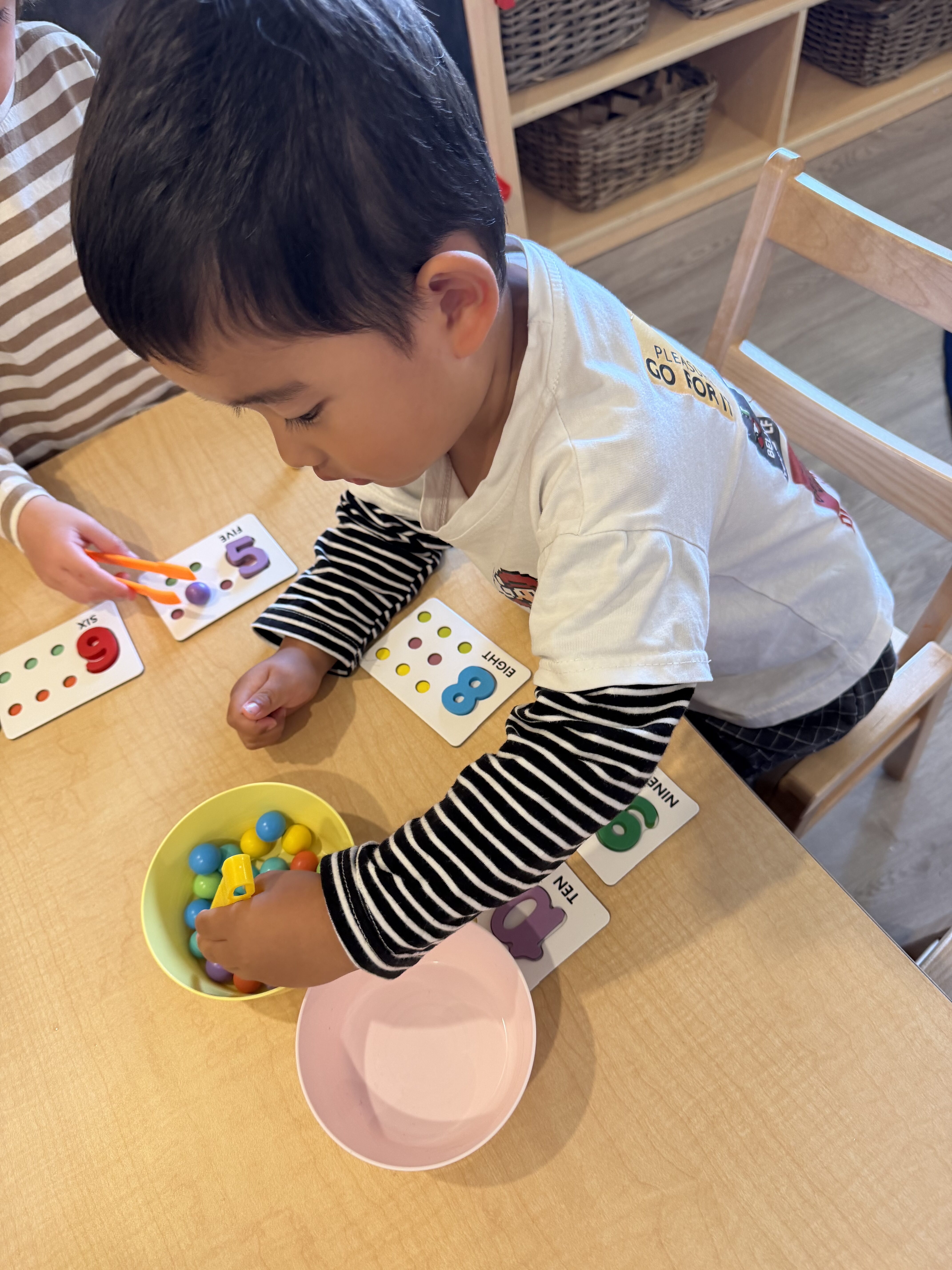 Children doing a counting activity with colorful pom-poms at Kinderly childcare