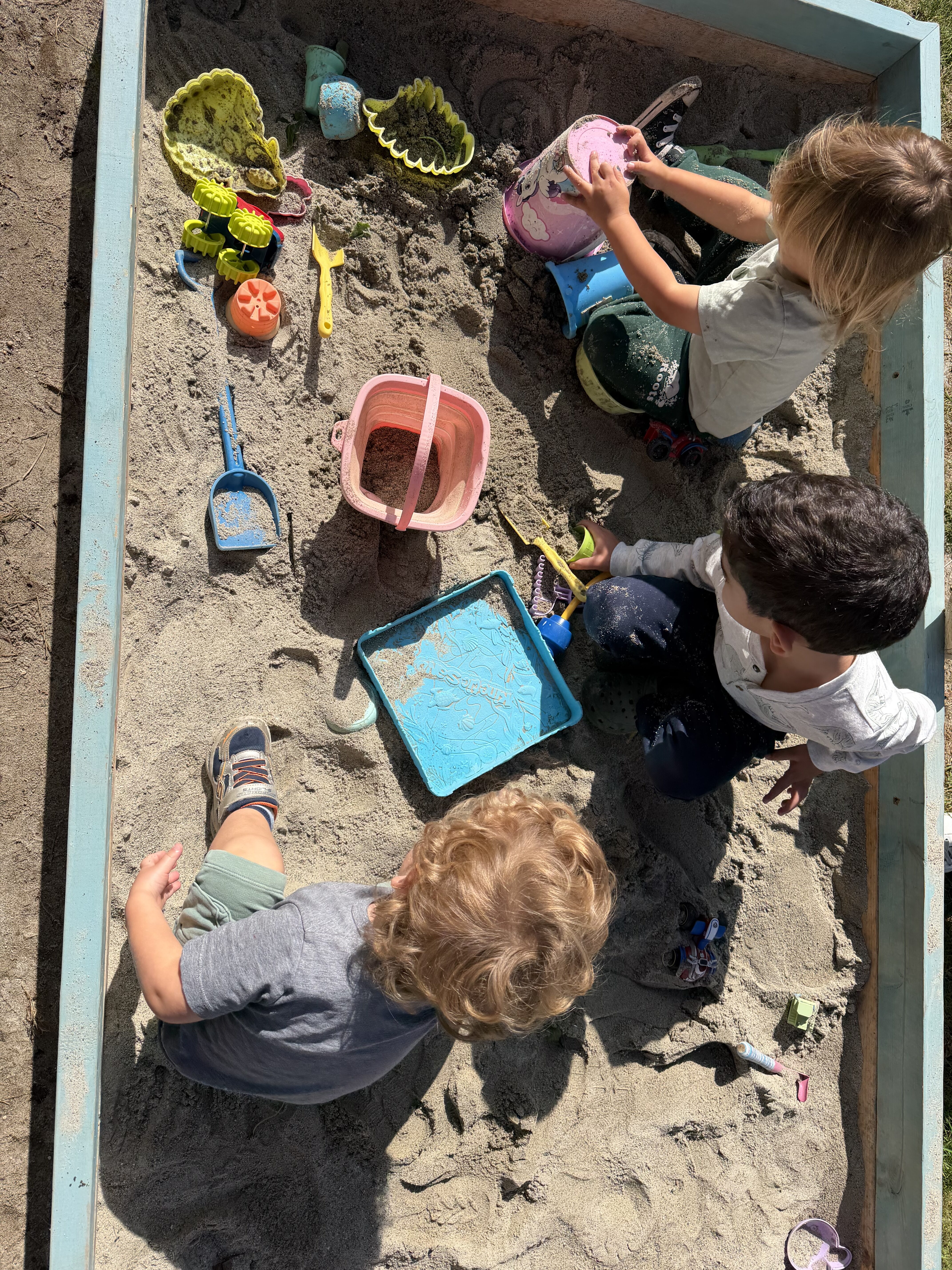 Children playing with sand toys in the sandbox at Kinderly childcare