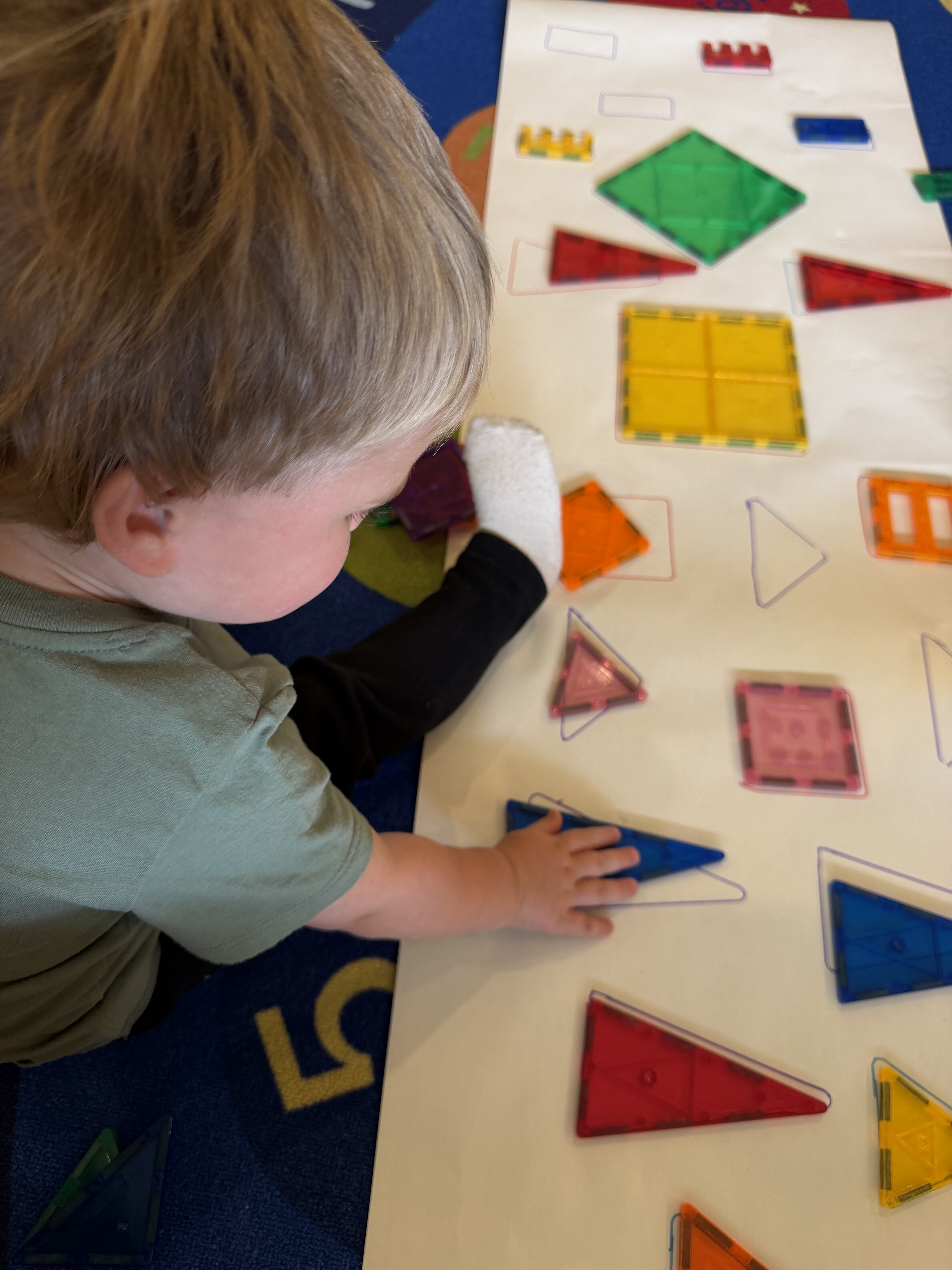 Child playing with colorful magnetic building tiles at Kinderly childcare